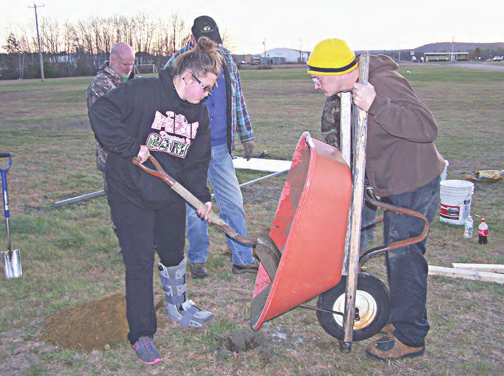 POURING THE CEMENT Jade Bailey, left, and her father Russ pour the cement into the post holes prior to installing a new sign at the entrance of Orange Municipal Airport denoting the location is also