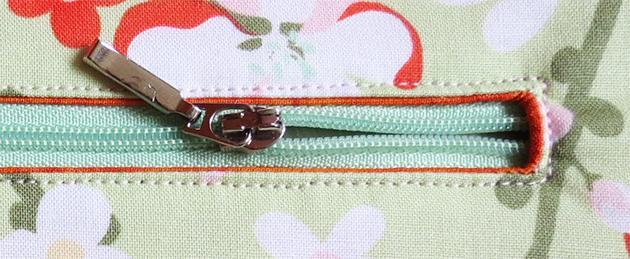 Position the longer zipper behind the opening.