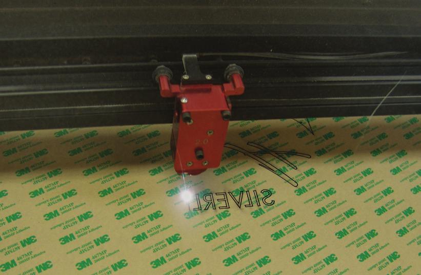 2.2: Vector cut the sign using Rowmark ADA Alternative plastic with the back side facing up and the backing paper in place. Cut using High Power Density Focusing Optics.