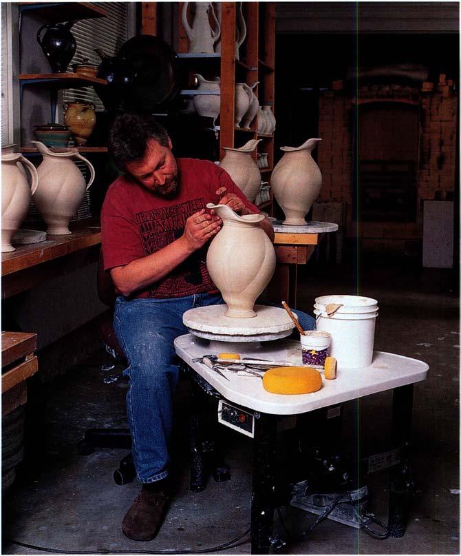 Adding a spout extension to a leather-hard melon pitcher; an important design consideration is the line that begins at the tip of the spout, sweeping across the rim and continuing down the handle in