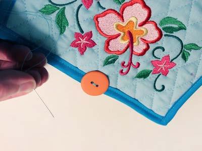 Add the button at the center of the top edge along the bias tape. Lay the towel flat with the wrong side facing up. Fold the outer edges in to the wrong side about 3".
