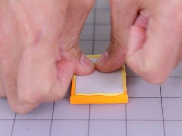 Use your thumbs to work the putty into all of the details and corners of the mold. Reuse the lid to help compress the putty into the part.