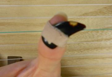 your finger two times (approximately five to six inches), and tape on the picks to the adhesive tape Second, tape the thumb pick on to the thumb The curve of the pick