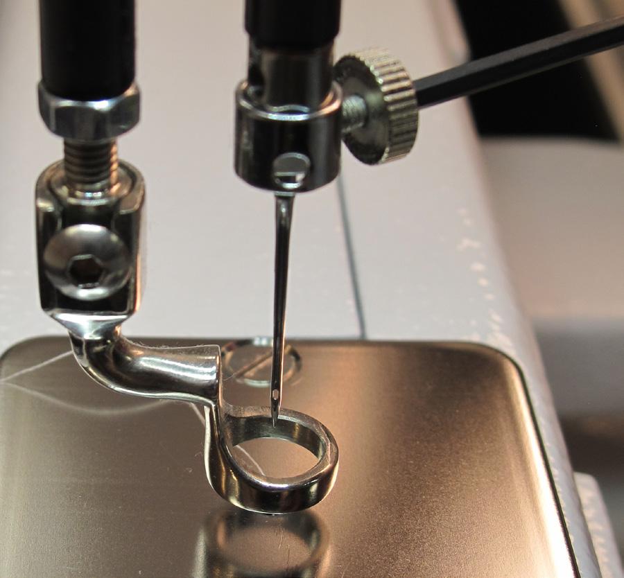 1. Move the needle bar to the up position by pressing the needle up/down control on the handles. 2. Turn off all power to the machine. 3. Loosen the needle bar clamp screw with the 2.5 mm hex tool.