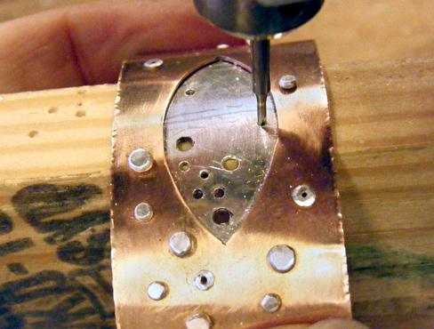 If you can fit the hammer within the bracelet, rotate the hammer to hit the rivet perpendicularly to the first few strikes. This will flare the rivet into the bevel more evenly.