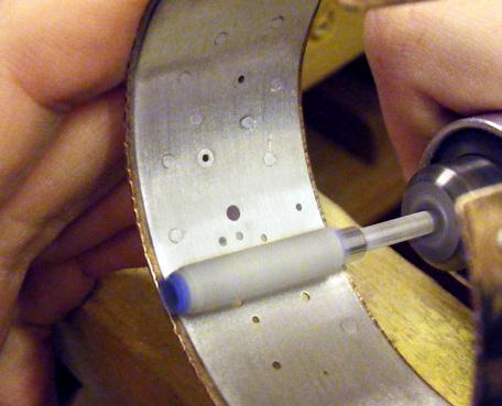 Now that the first rivet is securely holding the two strips of metal together, drill the remaining 1 mm holes through the liner, and repeat the previous steps to bevel them and set wire rivets in