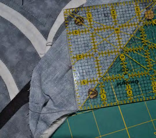 Place the 45 line on the ruler along the raw edge of the quilt.