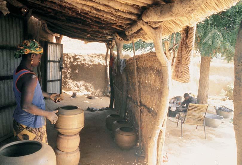 4 WASA S FAMILY Working in the vestibule of her compound, the woman in the pink shirt is beginning to make a pot by forming a slab over a mold.
