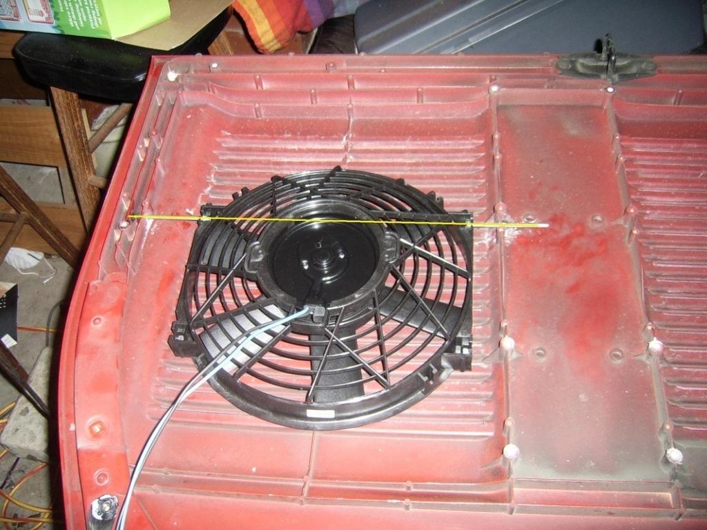 Remove fan from packaging and place onto the left side of lid (looking at it with the hinge mounting points at the bottom). Orient the fan so the leads are at the bottom, and the fan sits square.