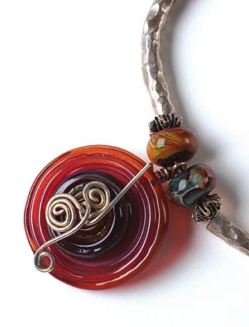 Materials 8 assorted 14 8mm borosilicate (boro) rondelles 1 purple 22mm lampworked glass disc 1 red-and-orange 38mm lampworked glass disc 12 Thai silver 9 6mm spacers 6 Thai silver 6 55mm hammered