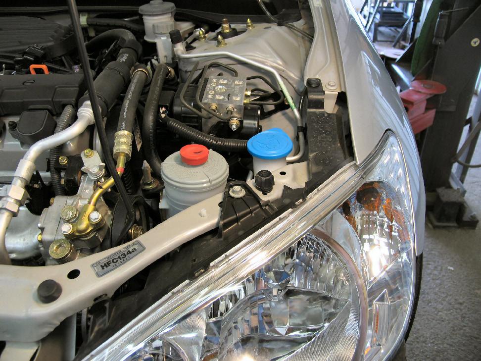 Using a 10MM socket, remove one metric bolt from above the headlight assembly, as indicated by the grey arrow in the photo above.