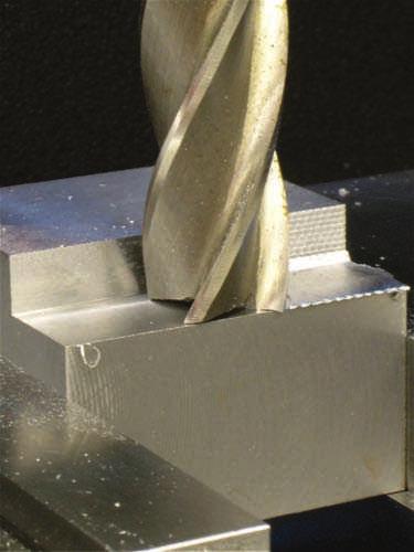 This sets a reference for the width of the step. (See Figure 6.3.70.) Then move the saddle so the endmill clears the workpiece, positioning the tool for conventional milling.