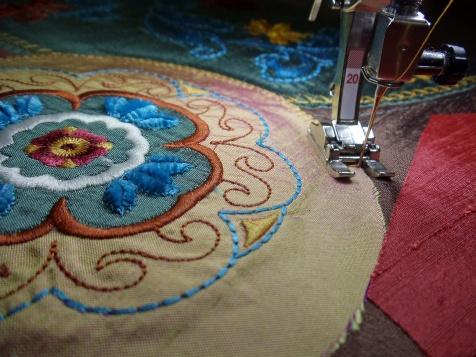 fuse a 9 square of fusible web to the back of Centering the stitched design, cut a 7 -diameter circle from the fabric piece.
