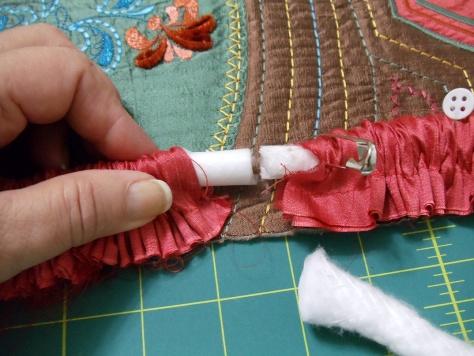 Fold the strip in half lengthwise, wrong sides together, and stitch ½ from the raw edges. Insert the 2 yard length of cording into the tube using a bodkin.