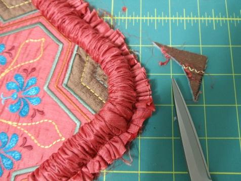 Trim away the pillow top fabric at the corners to match the curve of the cording. Press the seam allowances flat.