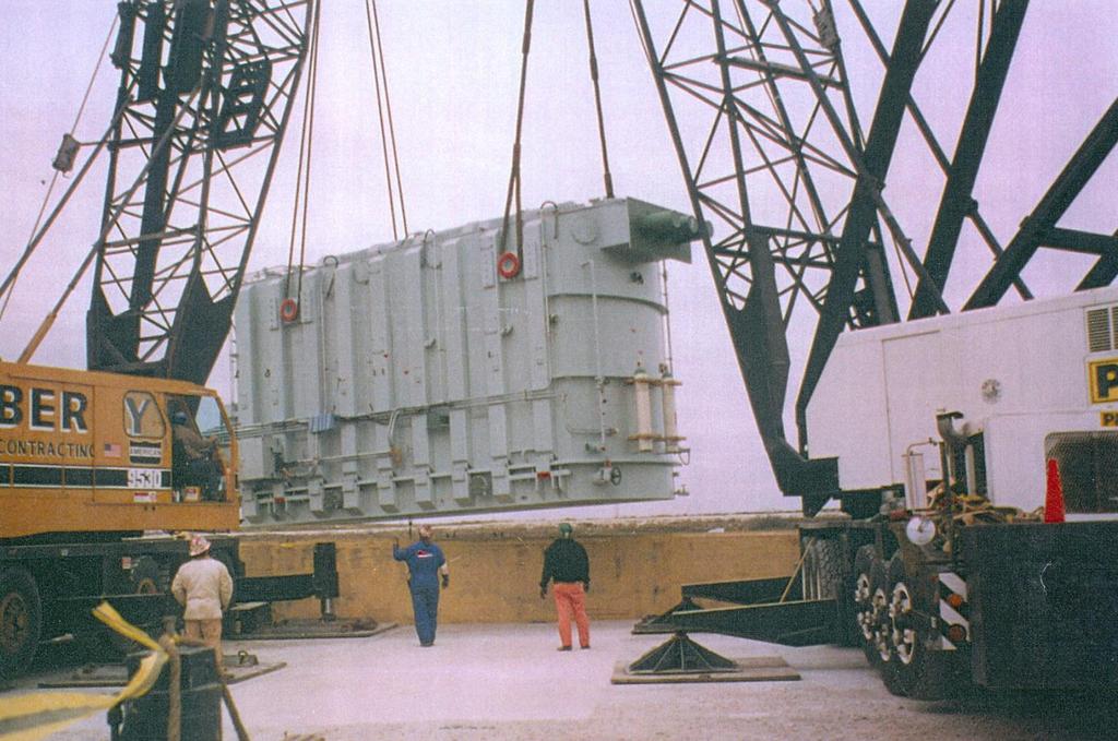 TWO CRANES OFFLOADING A TRANSFORMER FROM A