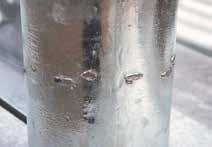 It is caused by incorrect abrasive blasting procedures creating shattering and delamination of the alloy layers in the zinc coating.