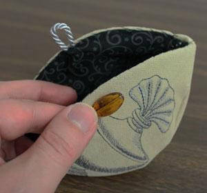 To create the closure, sew an oblong bead in the center of the right side of the opening. Cut a 3" length of cord, form it into a loop, and tape the raw ends together.