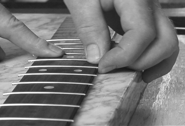 Level the dots with a smooth mill file (or the 120-grit edge of the carpenter s level used earlier). Use a light touch in sanding so you don't alter the fretboard edge.