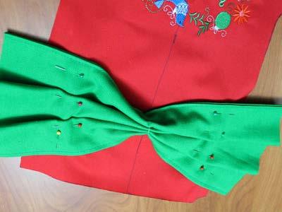 Create two pleats on both sides of the bow and pin in place. Place the bow at the top of the embroidered front piece.