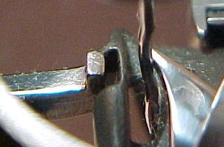 Most of the notch needs to remain unobstructed to allow the top thread to pass through the gap between the end of the hook retaining finger and the notch in the