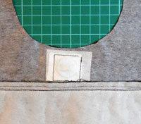 Cut a square of heavy interfacing approximately 1 ½ inches square and iron it to the back of the lining piece on top of the light weight lining and centred over the marked dot.