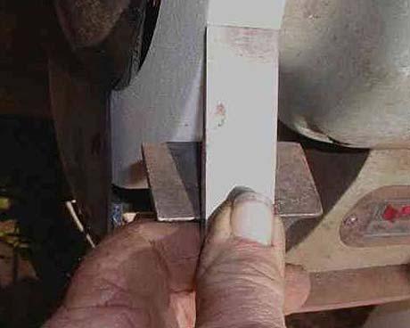I use a friable grinding wheel for my edge tools. These are usually white, but I have seen pink ones. Grasp the tool between your thumb and forefinger as shown above.