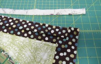 The fold should be even with the cut edge of the first side. Wrap the binding around to the back of the quilt and hand stitch (or stitch-in-the-ditch) it in place.