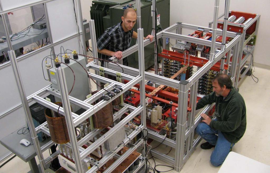 Robert Martin (left) and Robert Ice (right), WVHTC Foundation researchers, make adjustments to an experimental power converter that may someday provide an emergency replacement for transformers