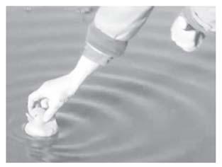 He uses a rubber duck to make circular ripples on a pond of still water. The teacher moves the duck up and down.