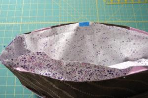 the bag). Keep top raw edges even, and pin at fabric sides to hold in place. If needed, use clips or masking tape to hold fabric to the top Kraft-Tex panels.