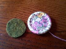 Place the felt ring on the back of the button and oversew the felt neatly onto the back
