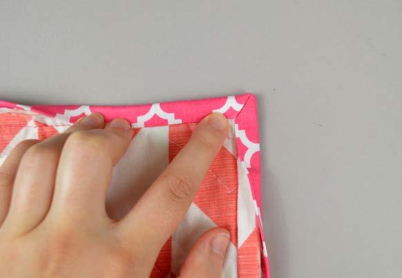 At the corners, the binding should be folded as the photo shows. Fold one side so the corner makes a diagonal, then bring the other side over to make a neat mitered corner.