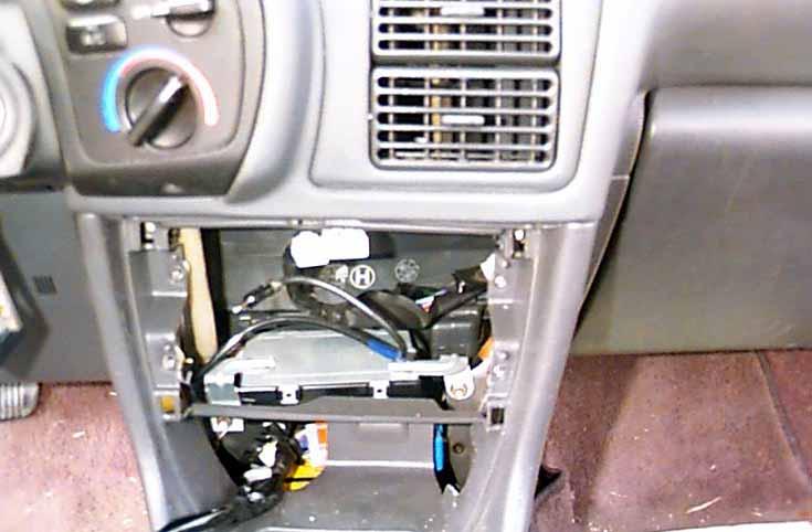 To unsnap the top of the plastic dash panel, insert a flat head screwdriver above the top of the plastic panel in order to