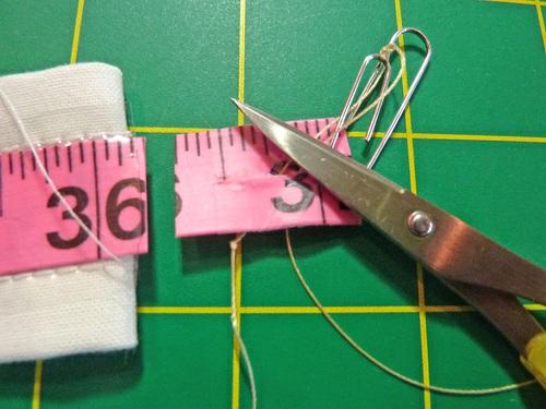 17. Using a small pair of needle nose pliers or tweezers, reach into the left open end, gently and carefully grab the head end of the tape measure (the metal end), and slide the tape measure back