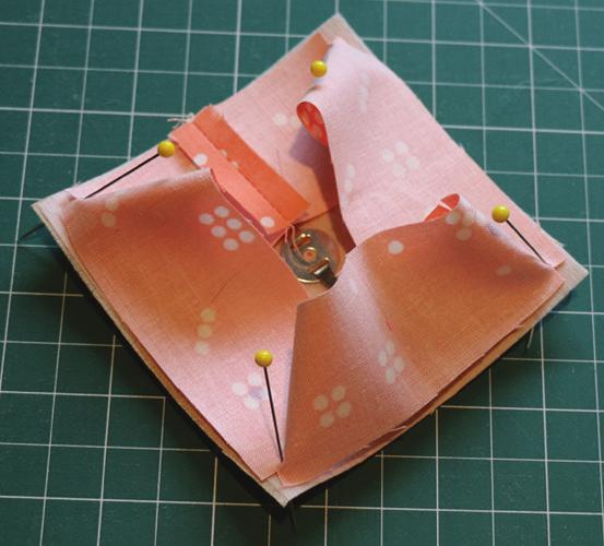 With right sides together, pin the rectangle to the pincushion top (the square without the metallic clasp), centring the rectangle seam on one edge and aligning the dots at the corners.