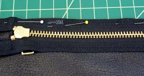 The edge of the zipper tape should be even with the fabric's raw horizontal edge. Make sure the zipper is centered between the left and right sides of the panel.
