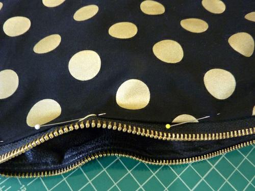 The top folded edge of the lining should fall below the zipper teeth by about ⅛". If it doesn't, adjust the fold to fit and gently re-press. 18. Pin the layers together. 19.