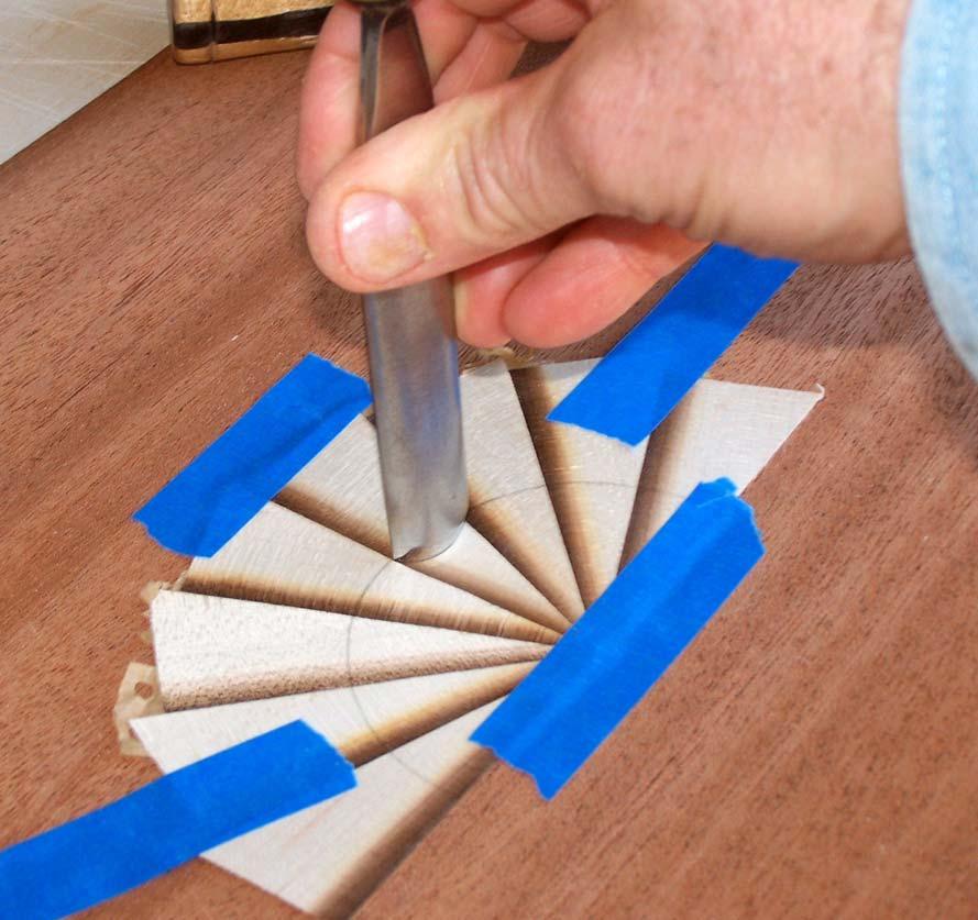 Rap the gouge with a mallet, cutting through both pieces of veneer in one stroke.