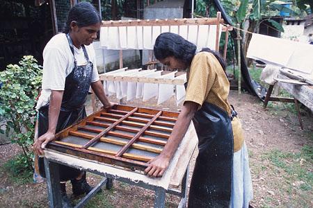 Another felt is placed on top of the paper, followed by another paper sheet and so on until a stack has been built up. Figure 11:. E D Karunawathi and Shanthi Dassanayake pressing to remove water.