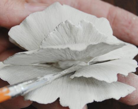 Examine the flower carefully for any holes or unwanted spaces where the leaves meet the base; use syringe metal clay to fill these gaps, letting it dry completely before proceeding. Form the bail.