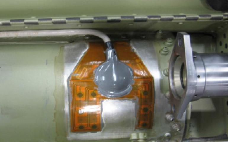 Figure 1.4: SMART Layer sensor installed on an OH-58D tailboom in order to monitor the golden rivet region of the structure. The layer contains 8 piezoelectric sensor/actuators (figure from Ref.