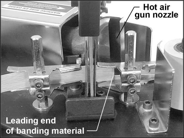 4. Position the leading end of the banding material in front of the nozzle of the hot air gun, as shown in Figure 10. 5. Choose the desired heat setting on the temperature dial. 6.