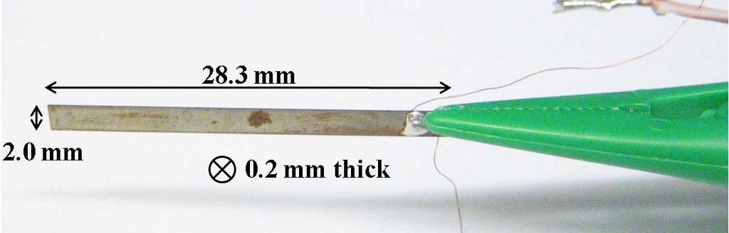 Figure 12: Metglas/PZT/Metglas laminated heterostructural composite, provided by Carmine Carousella, held by tweezers to enable resonance bending modes during testing.