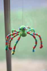 Glue - pom poms on the center, with a hot glue gun, to make a body and head/ face. Thread on beads to each leg and hang it in a window!