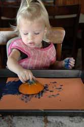 Then stamp the paint covered pumpkin on a piece of paper to make pumpkin prints. Tape the paper inside the tray to hold it in place!