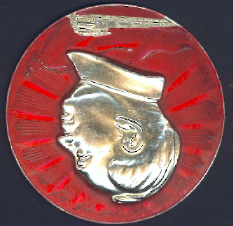Mr. Klus' small collection of Mao Pins metal pin with raised silver Mao profile surrounded by red field with radiating lines. Red banner in low relief. Silver train heading left across bottom of pin.