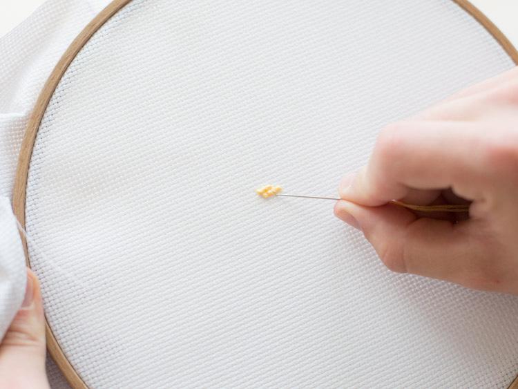 Next, you could work your way down and embroider more cross-stitches with the light brown yarn.
