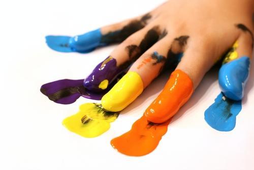 This image shows a child's fingers dipped in paint colors and smeared on blank paper.
