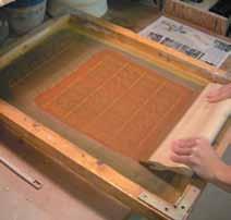 Use a metal rib to remove excess slip from the silk screen (figure 5).